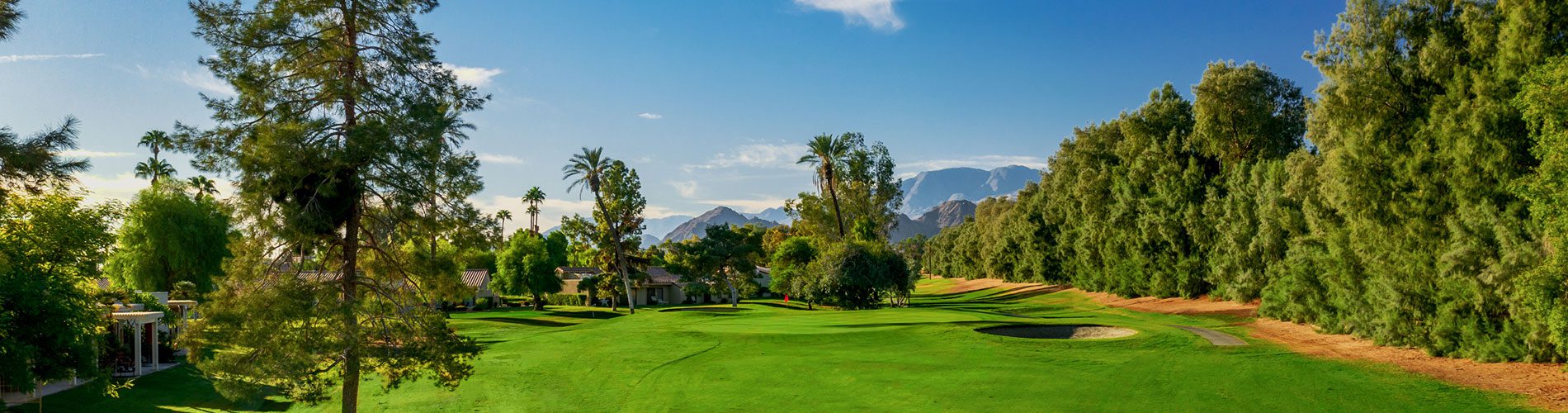 A golf course with trees and mountains in the background.